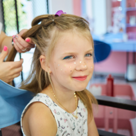 Meisje bij de kapper tijdens het verzorgen en stylen van kinderhaar met natuurlijke haarproducten