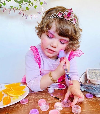 Op deze afbeelding zie je een meisje was enthousiast haar roze veilige kindermake-up van No Nasties aanbrengt.